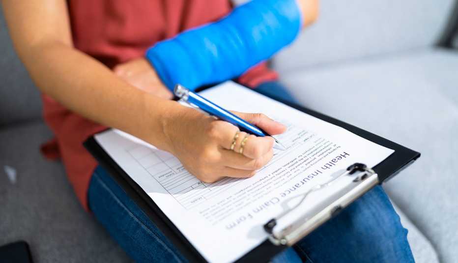 Manos de una mujer con una lesión en el brazo mientras llena un formulario