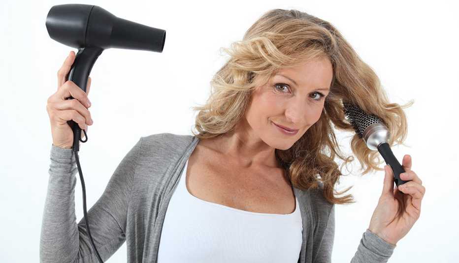Mujer con secador y cepillo de pelo en las manos