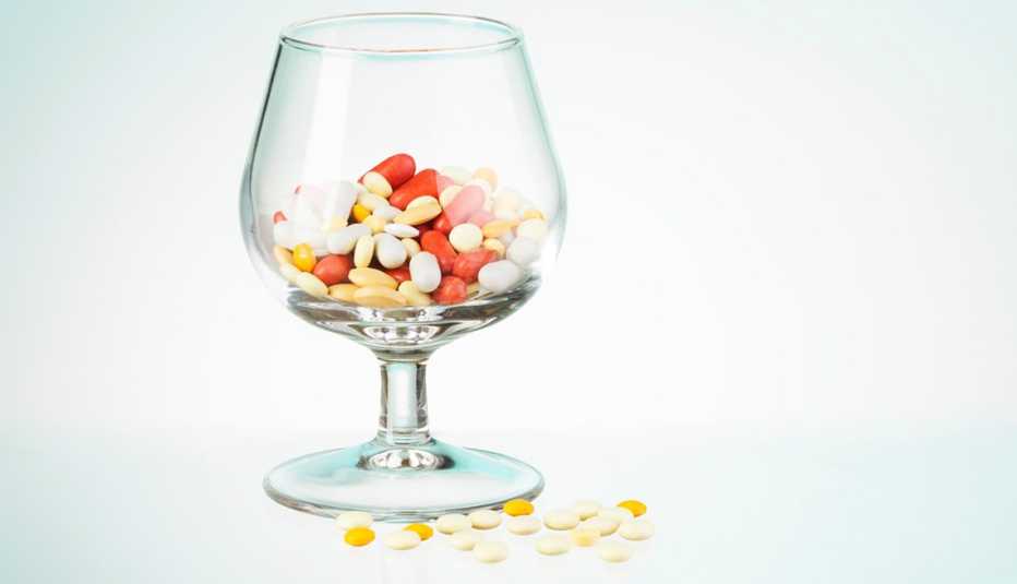 Copa de vino llena de medicamentos - Interacción entre medicamentos y el alcohol