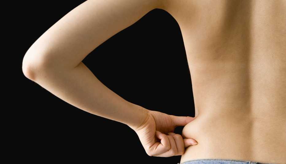 Mujer de espaldas agarrando su piel de la cintura - Preguntas al cirujano plástico