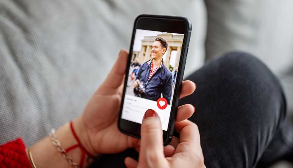 Manos de una mujer sostienen un teléfono que muestra un perfil de un hombre en una aplicación de citas