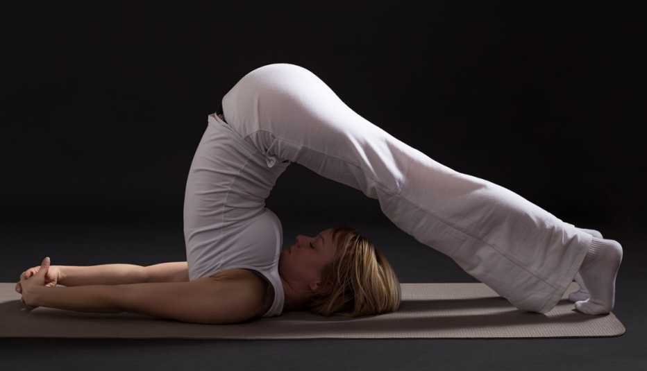Mujer realizando el halasana, pose de yoga