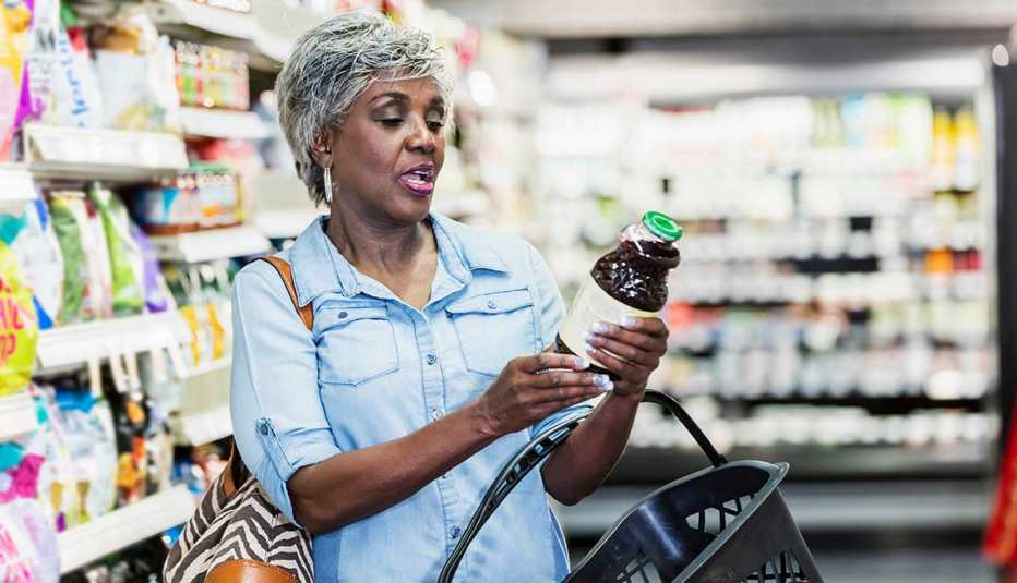 Una mujer lee la etiqueta nutricional de un frasco