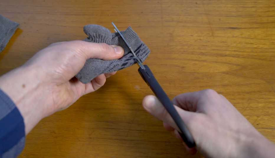 Manos usan una tijera para hacer un corte en una media