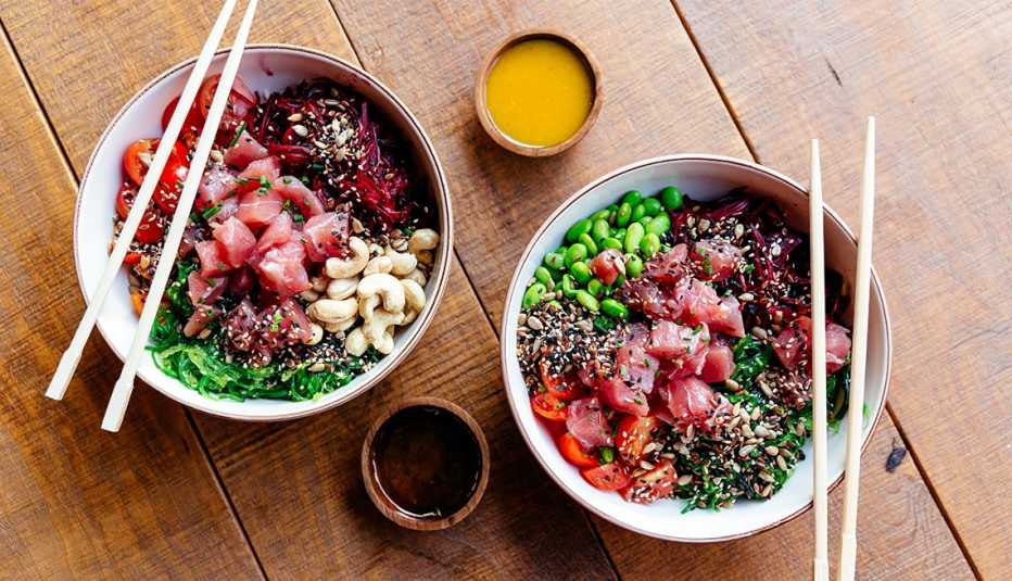 Dos poke bowls servidos con pescado crudo y vegetales