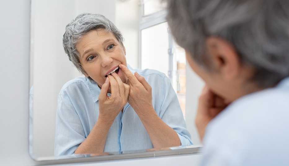 Una mujer limpia sus dientes con hilo dental
