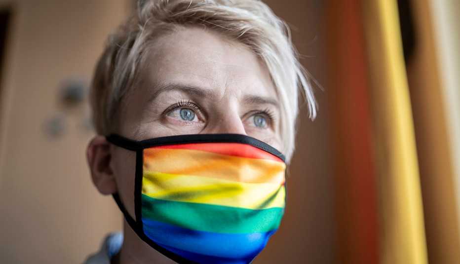Una mujer con una mascarilla con el diseño de la bandera LGBT