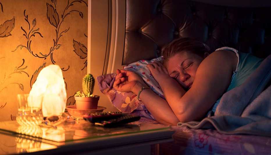 Una mujer duerme con una lámpara encendida