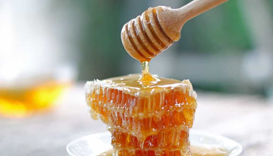 Cucharón de miel rocía miel sobre un panal