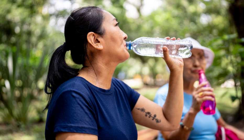 Dos mujeres toman agua mientras visitan un parque público