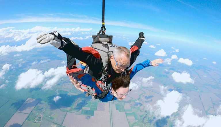 Mujer se lanza con su instructor de paracaídismo al aire.