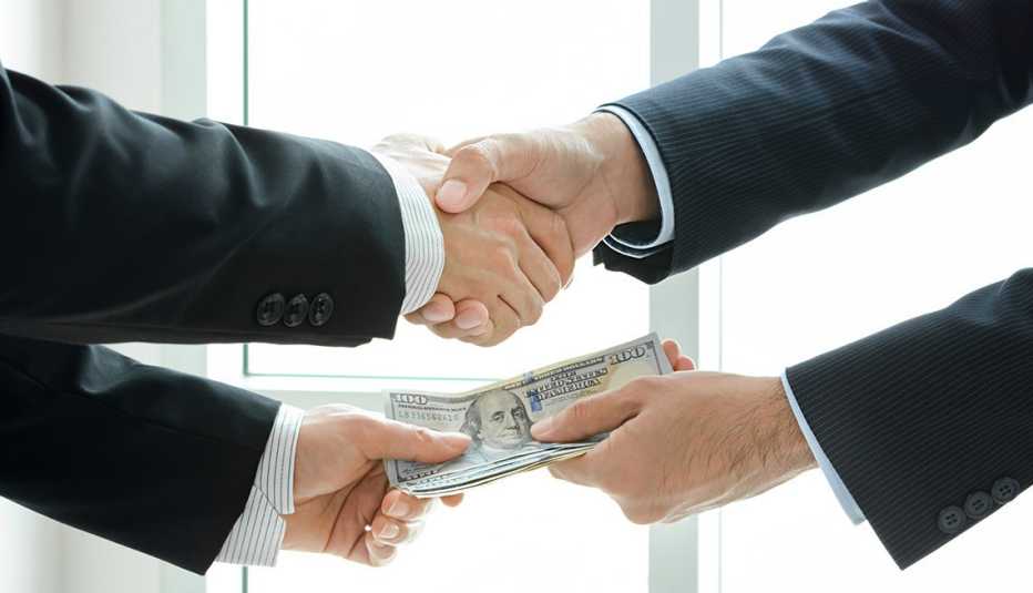 Dos hombres estrechando la mano e intercambiando dinero.