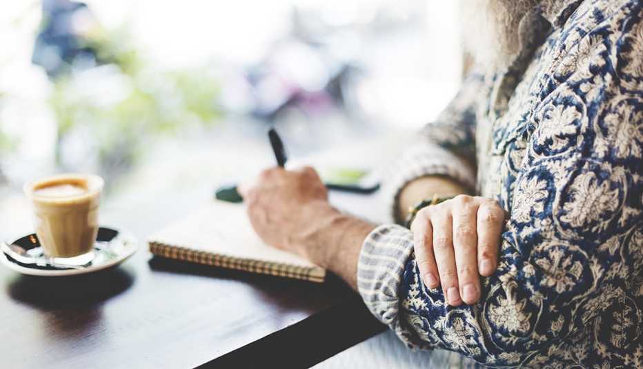 Manos de una mujer con un lapicero escribiendo en un cuaderno - Empleos con un salario anual superior a los 100 mil dólares
