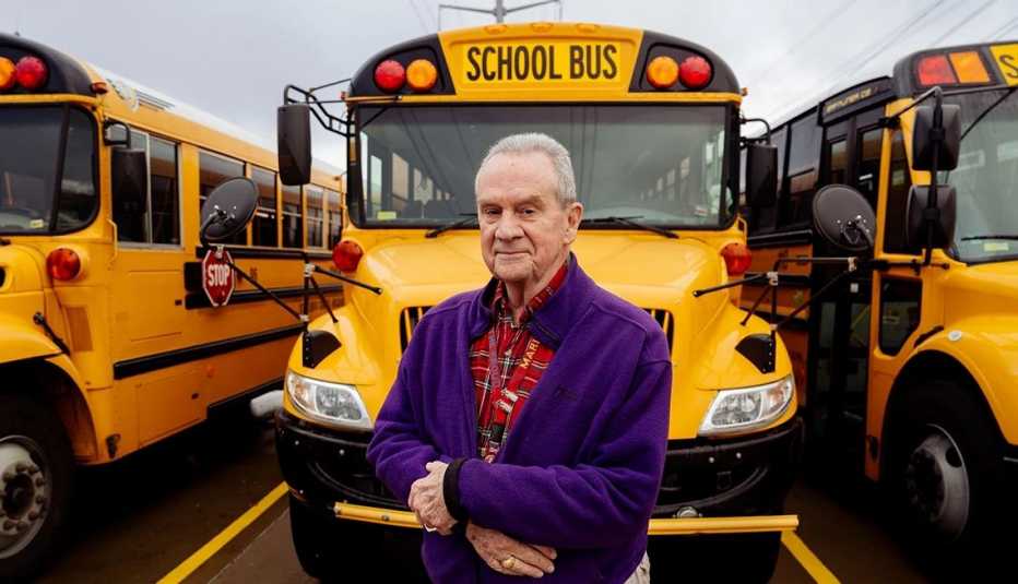 El veterano y conductor escolar Bill Goodbread posa frente a un autobus escolar amarillo