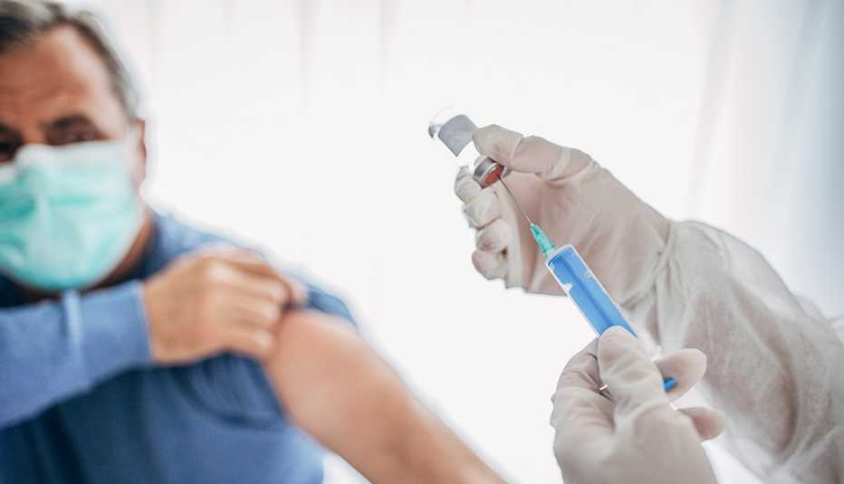 Hombre recibiendo una vacuna sobre su brazo.