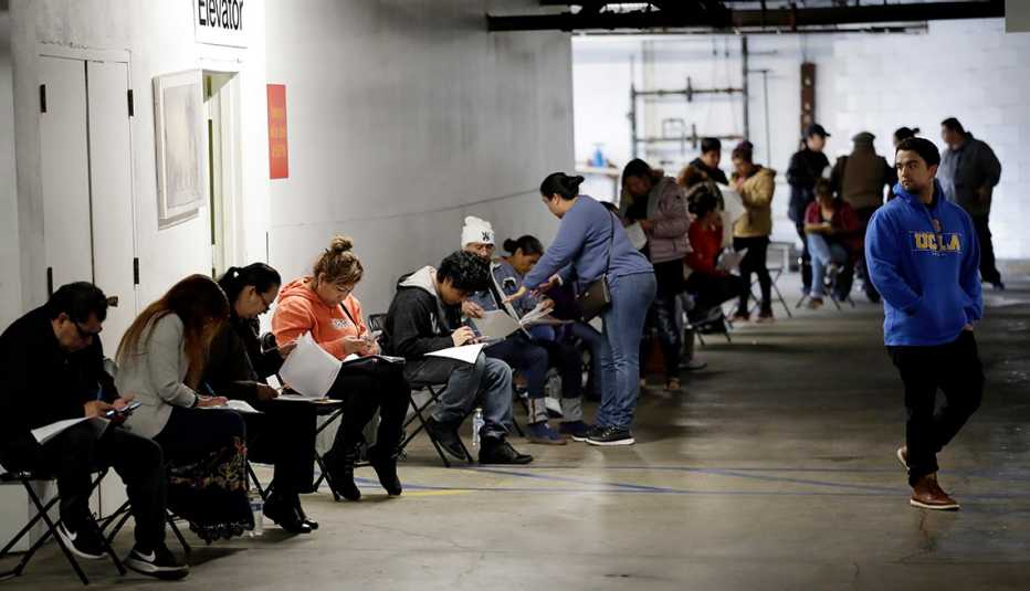 Personas llenando los formularios para los beneficios del desempleo, Los Ángeles, California.