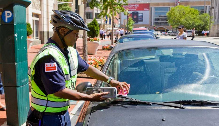 Agente de tránsito colocando un tiquete en un carro.
