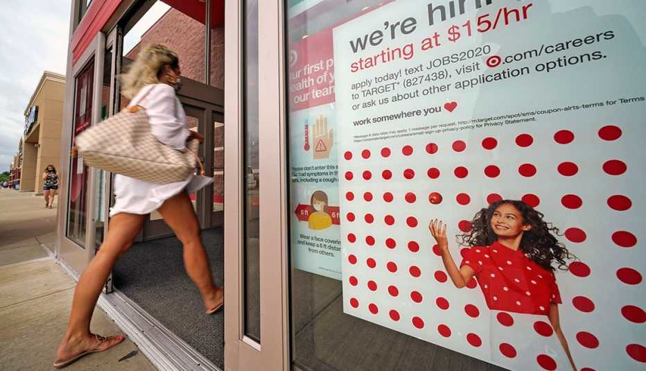 Mujer entrando a una tienda de Target, la cual anuncia en un aviso que están contratando nuevos empleados