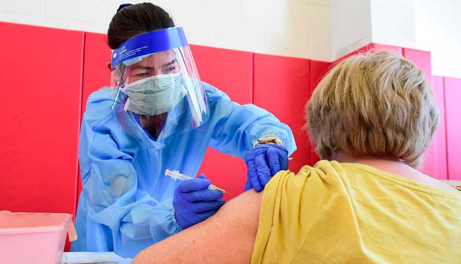Enfermera colocando vacuna contra la COVID-19 a una mujer.
