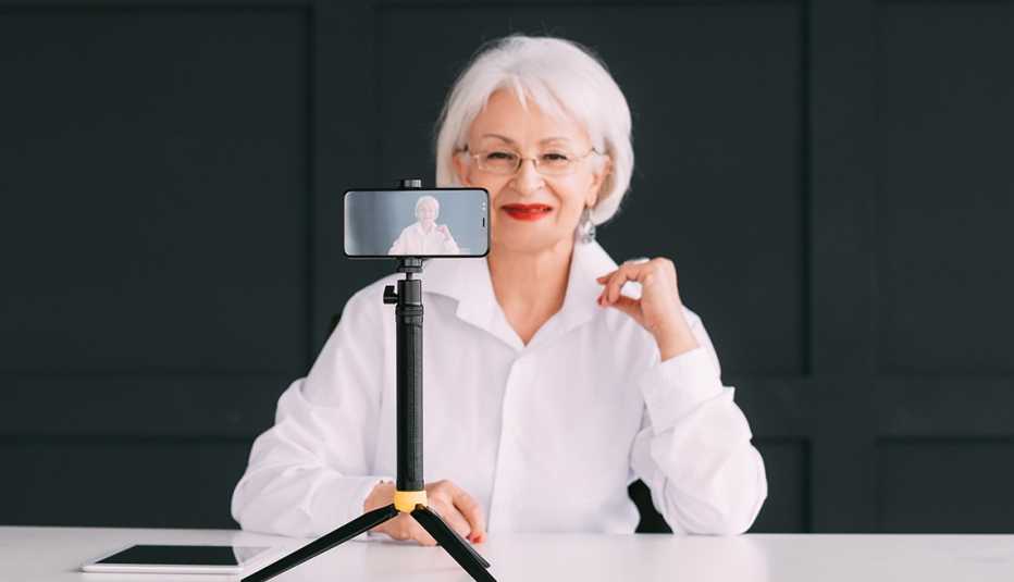 Mujer grabándose en video con su teléfono móvil sostenido por un trípode.