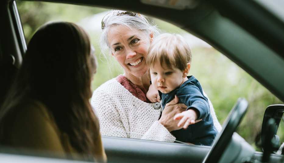 Mujer mayor sostiene a un bebé mientras habla con una mujer en un carro