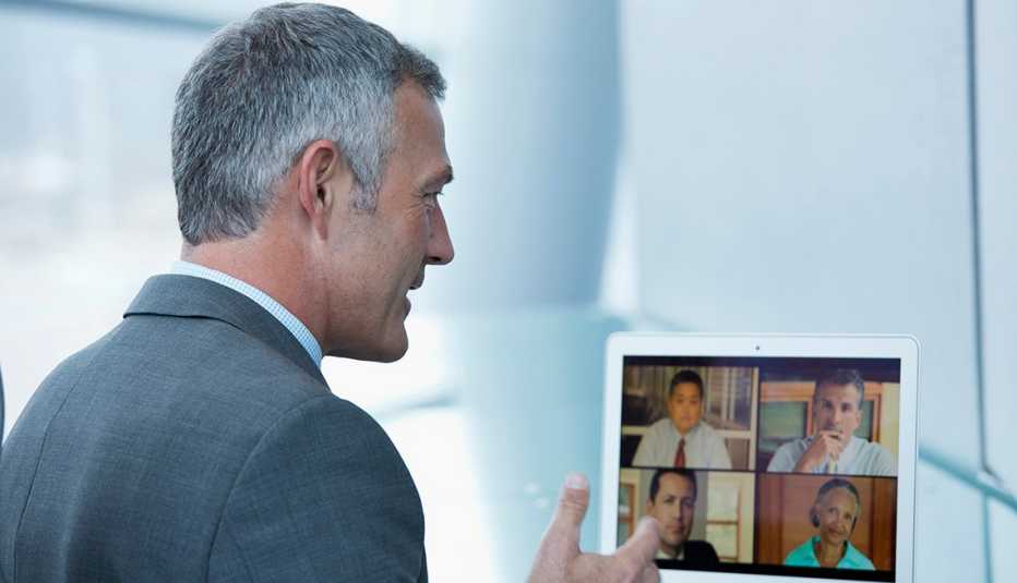 Hombre en traje de corbata desde su casa y haciendo una videoconferencia con otros colegas.