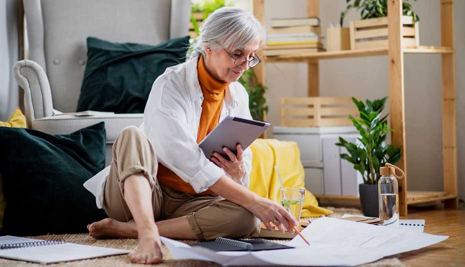 Mujer sentada en el suelo mientras trabaja en la sala de su casa