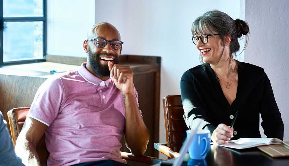Hombre y mujer riéndose en una oficina