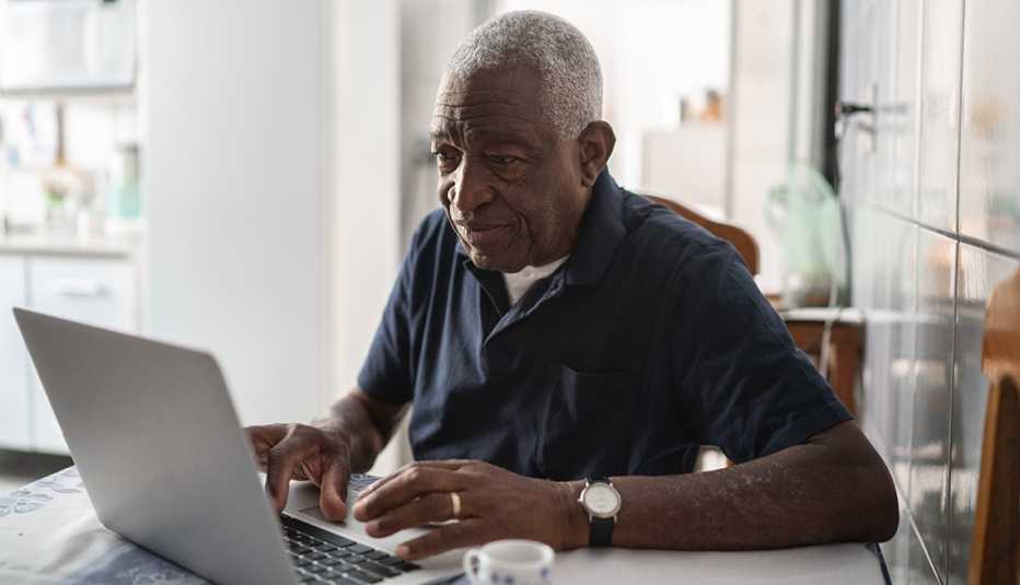 Hombre mayor trabajando en su casa desde una computadora portátil