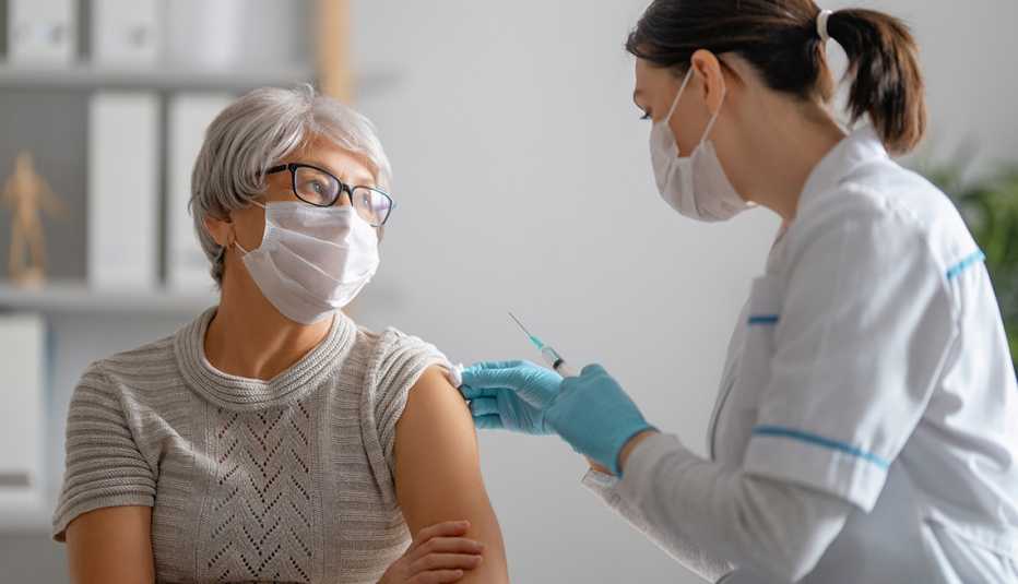 Doctora pone vacuna en el brazo a una mujer mayor.