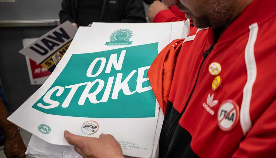 Una persona sostiene un afiche que dice en huelga