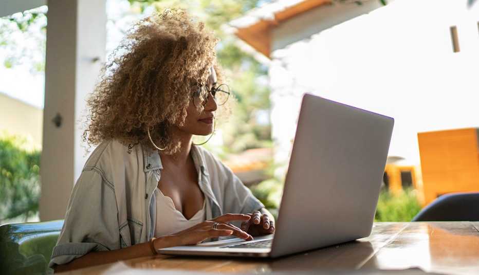 Mujer trabajando en su computadora desde el patio de su casa