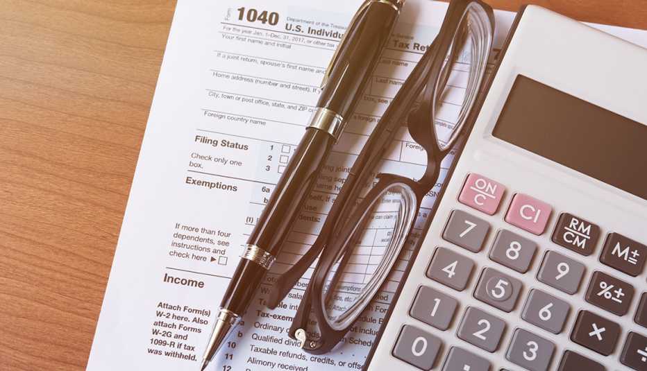 Forma 1040 del IRS enseguida de un lapicero, unas gafas y una calculadora
