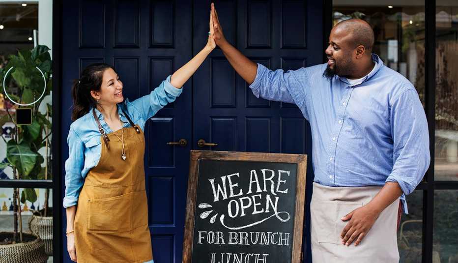 Mujer y hombre que chocan sus manos frente a un negocio 