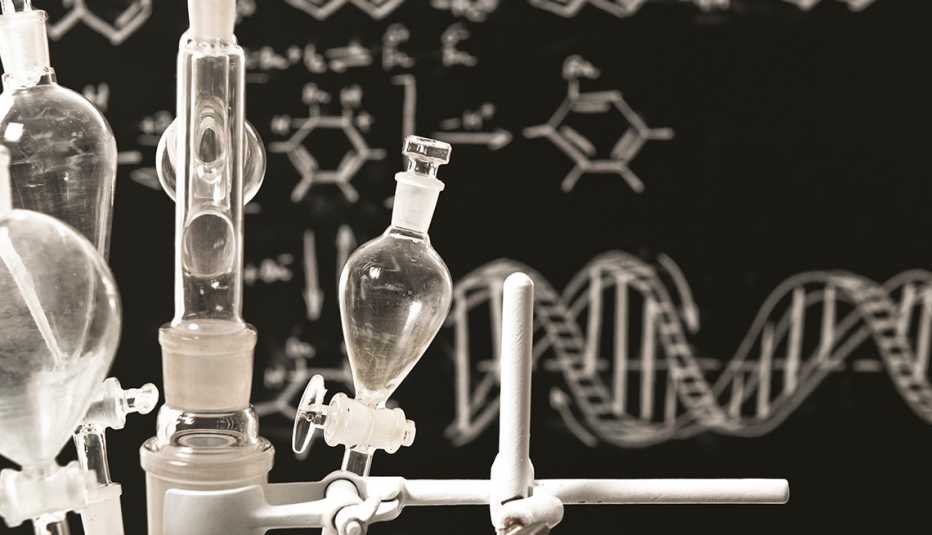 Instrumentos de un laboratorio y detrás estructuras químicas dibujadas sobre un tablero negro