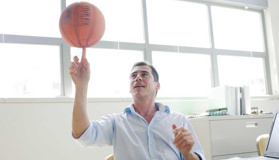 Ejecutivo en una oficina hace girar un balón de baloncesto en la punta de su dedo índice
