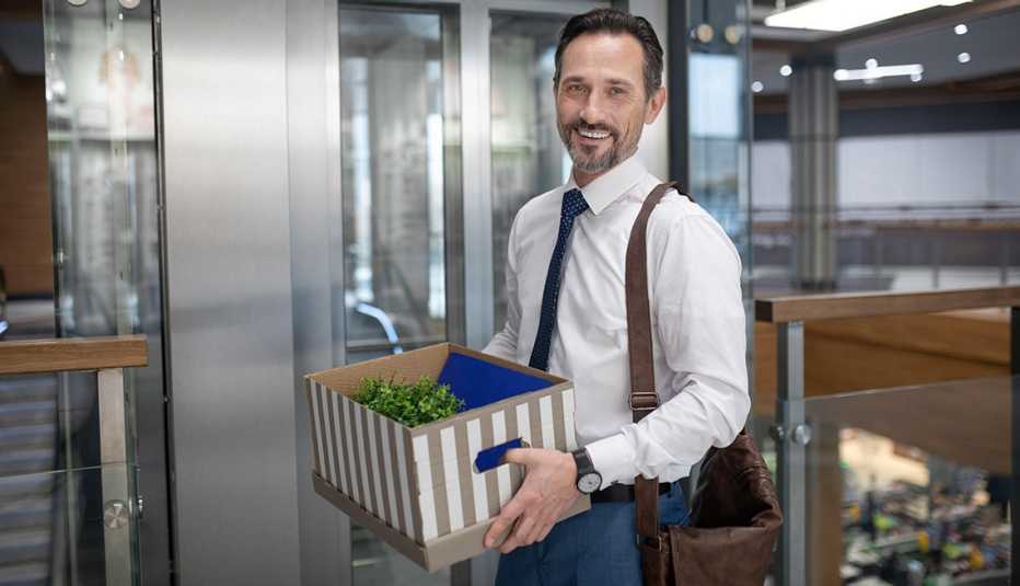 Hombre con corbata sostiene una caja con objetos personales en una oficina