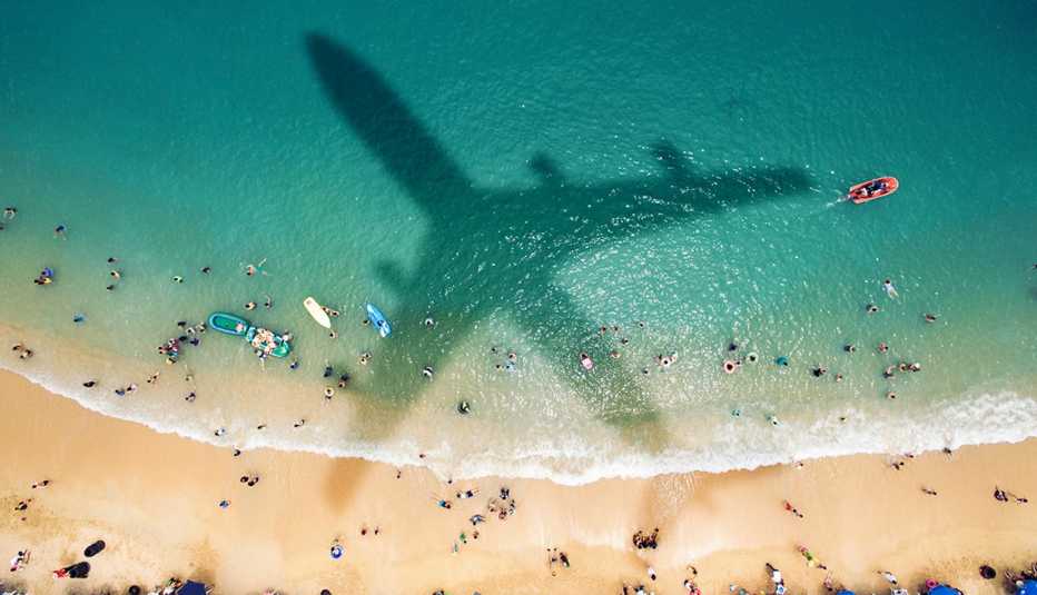 Estrategias para conseguir descuentos en viajes de último minuto - Sombra de avión pasando sobre el mar