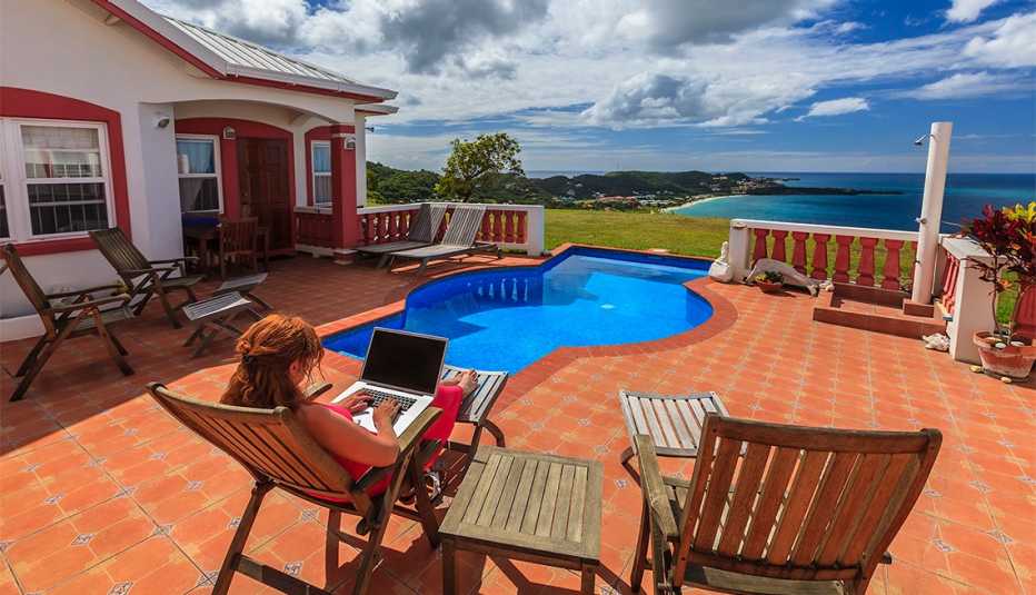 Mujer con un  laptop en la piscina con vista a la bahía de Grande Anse.