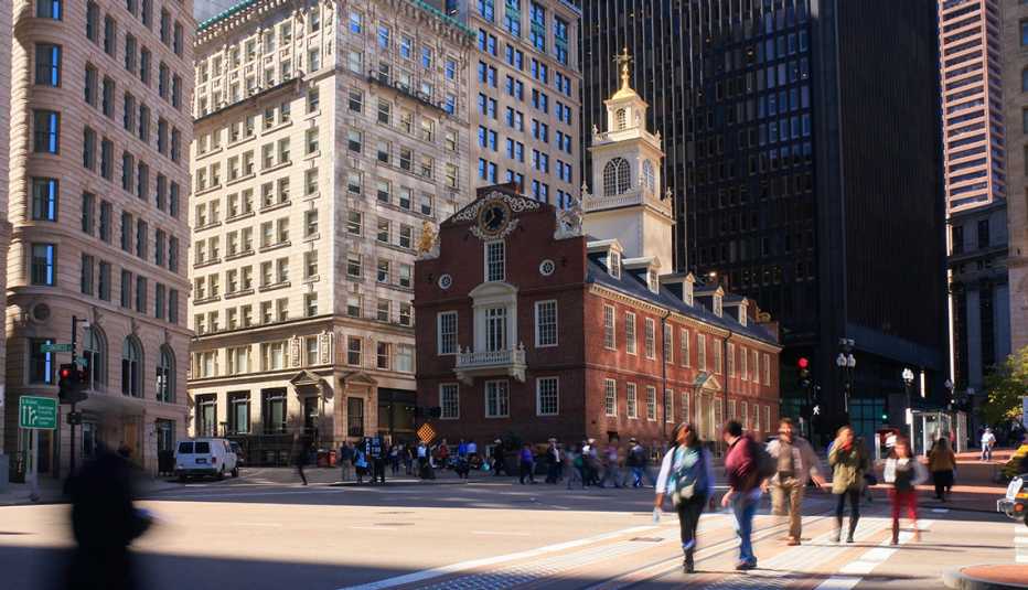 La imagen muestra al Old State House, una edificación antigua, ahora museo de historia, ya personas que cruzan en la concurrida intersección en el centro de Boston, Massachusetts.