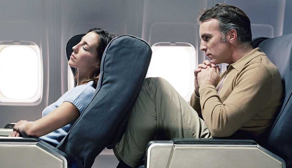Asiento de avión reclinado de la mujer en las piernas de un hombre