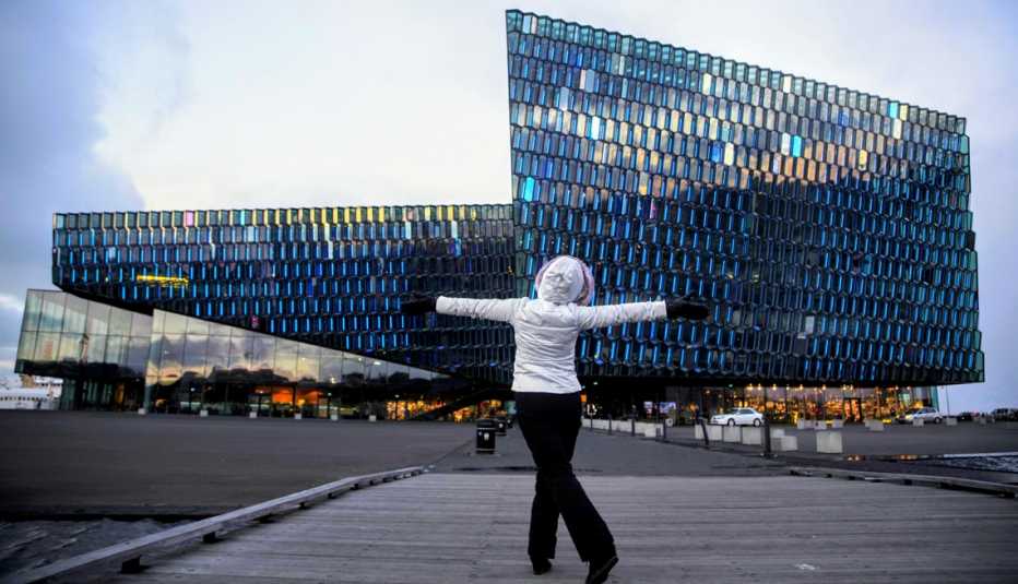 Carmen Dominicci abre los brazos mirando de frente a un edificio moderno