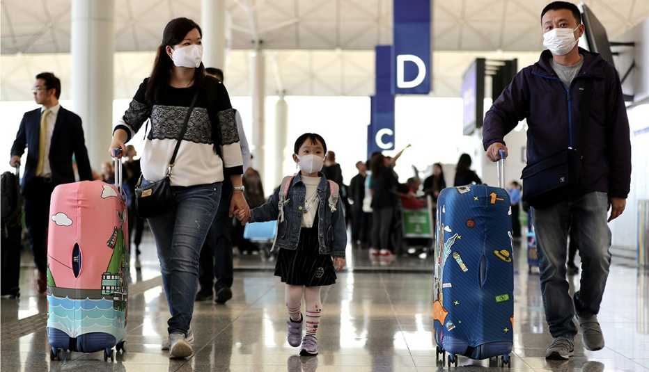 Viajeros con máscaras faciales caminan en el aeropuerto