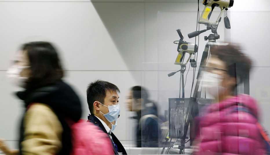 Personas transitan en un aeropuerto usando mascarillas para protegerse