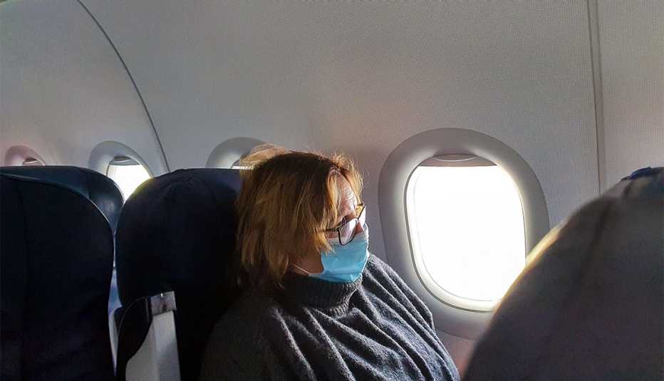 Mujer viaja en avión y lleva puesta una máscara médica