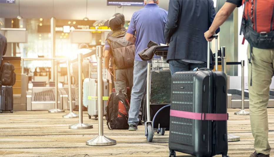 Pasajeros alineados en el aeropuerto para chequear su equipaje