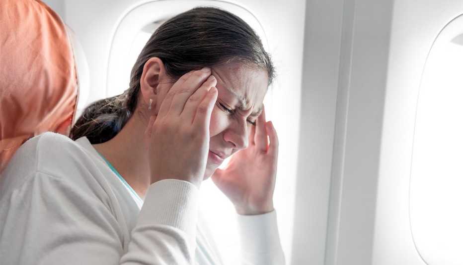 Mujer con dolor de cabeza en un avión
