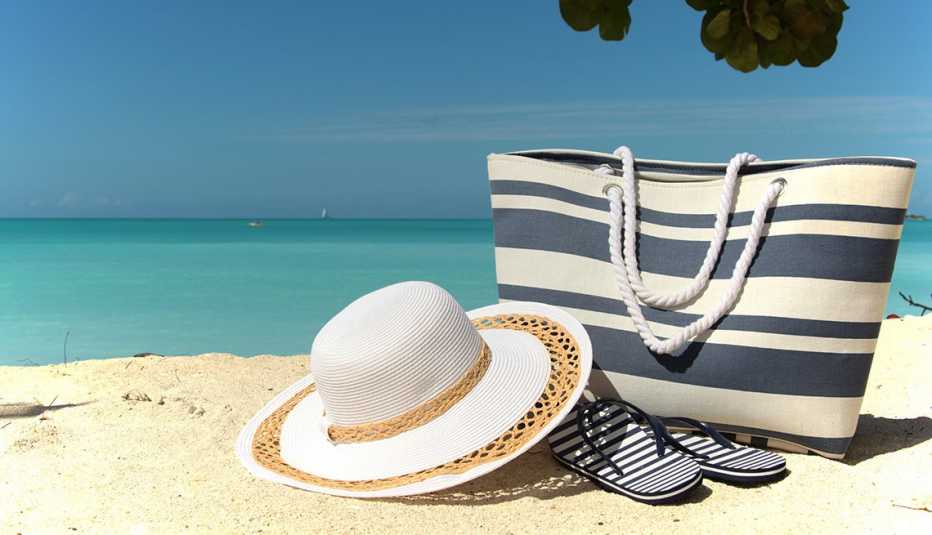Sombrero, bolso de playa y chanclas a la orilla del mar.