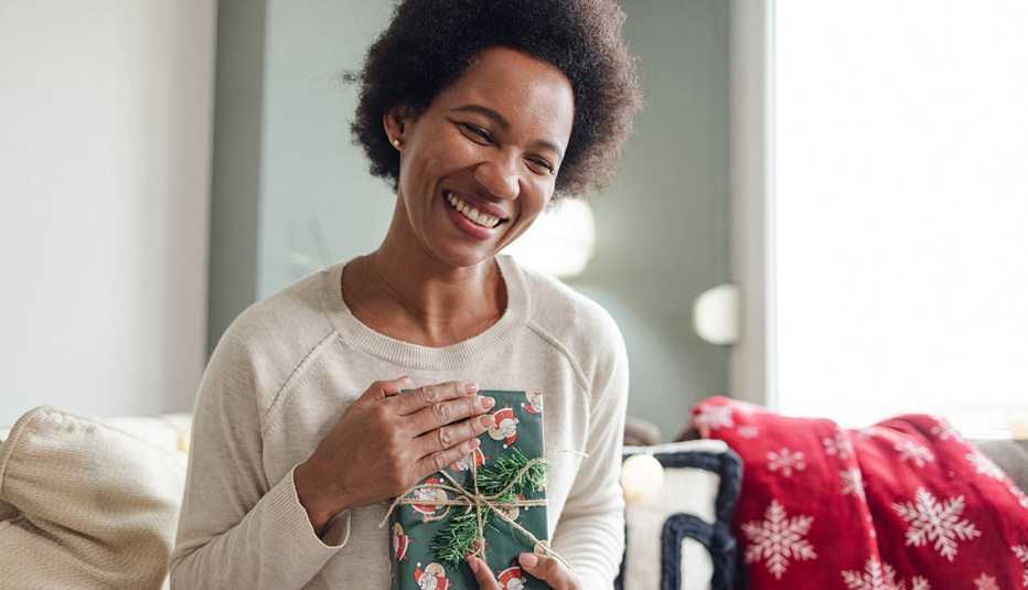 Una mujer sonrie al recibir un regalo de Navidad