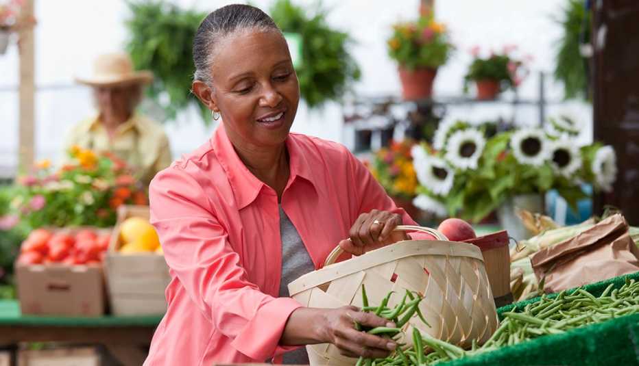 Mujer comprando vegetales en un mercado de agricultores.